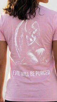 A person wearing a light pink short-sleeve T-shirt, shown from the back. The shirt features a large white sketch-style graphic of an angel and the text 'EVIL WILL BE PURGED' printed across the lower back.