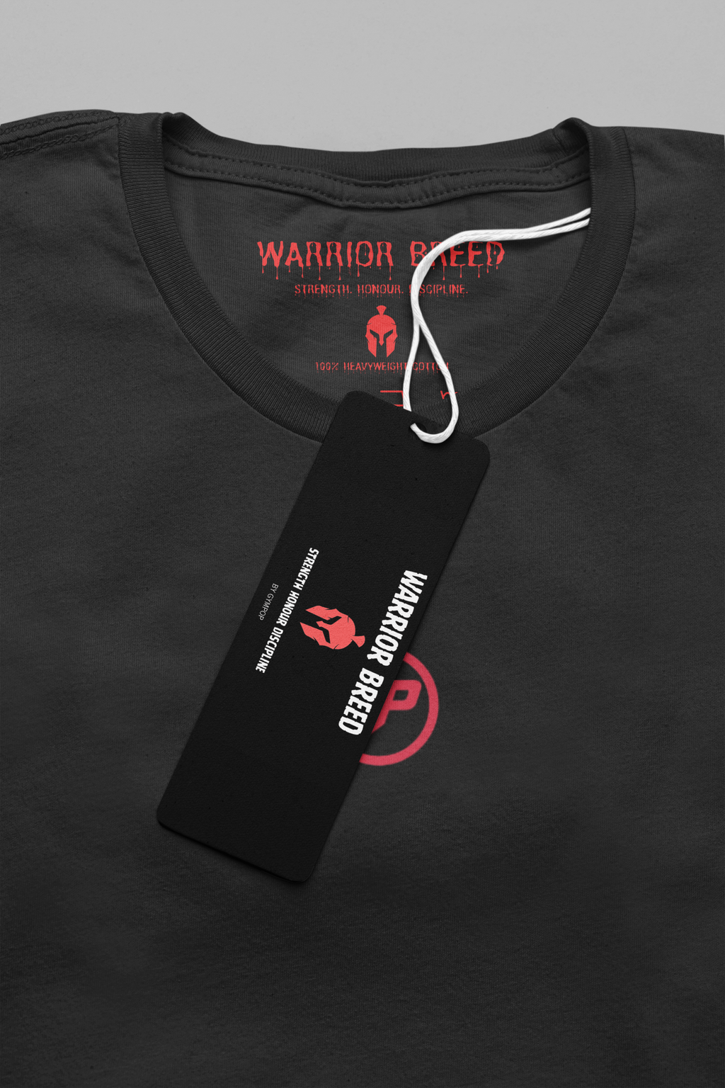 Close-up of a black Warrior Breed t-shirt with a black hangtag and red printed GP logo on the chest, shown against a neutral grey background.