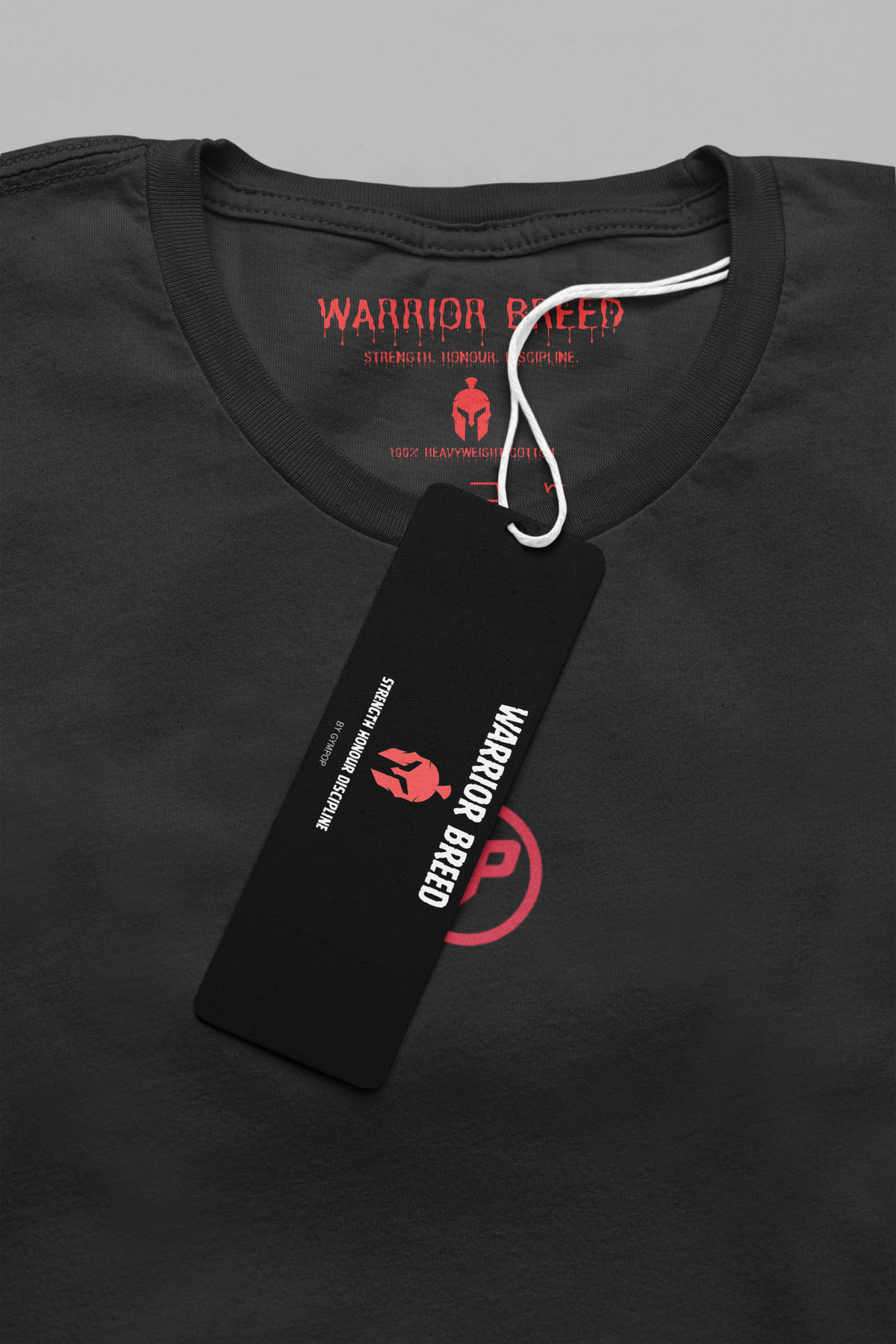 Close-up of a black Warrior Breed t-shirt with a black hangtag and red printed GP logo on the chest, shown against a neutral grey background.