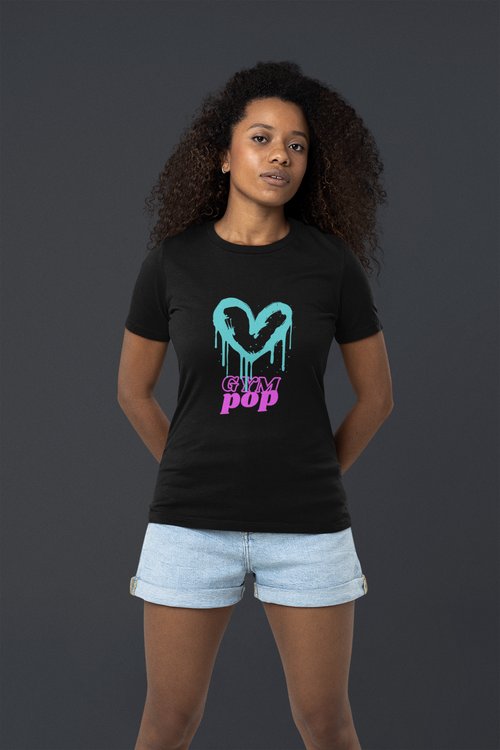 Woman with curly hair wearing Gympop Graffiti Heart Signature Tee, posing in a studio with a Bella+Canvas t-shirt.